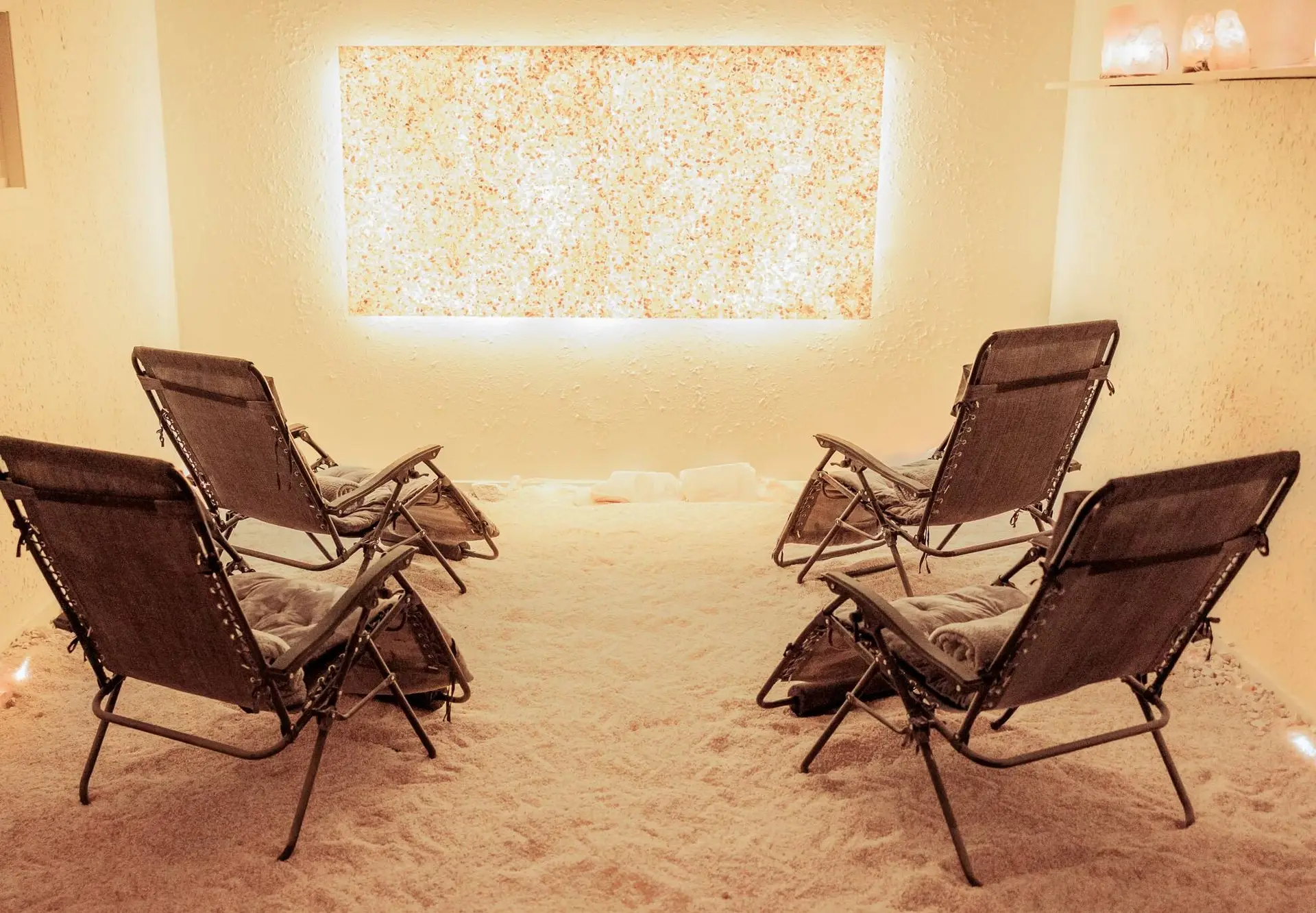 The salt room at Salt Cove Spa, with a backlit salt wall and reclining zero gravity chairs