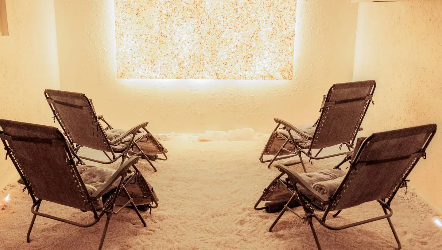 The salt room at Salt Cove Spa, with a backlit salt wall and reclining chairs on a salt floor
